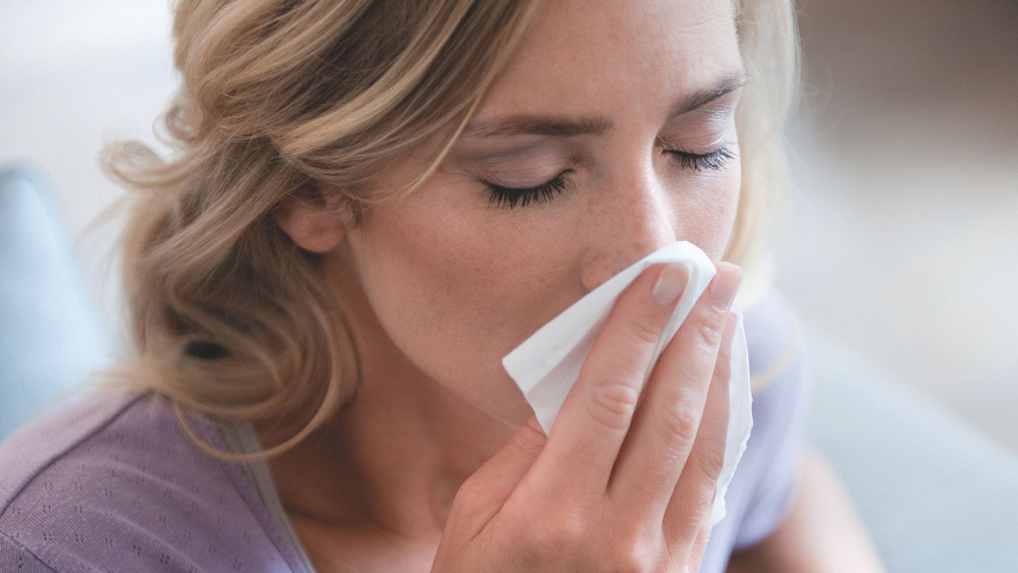 Kobieta wydmuchująca nos z powodu alergii na pyłki.