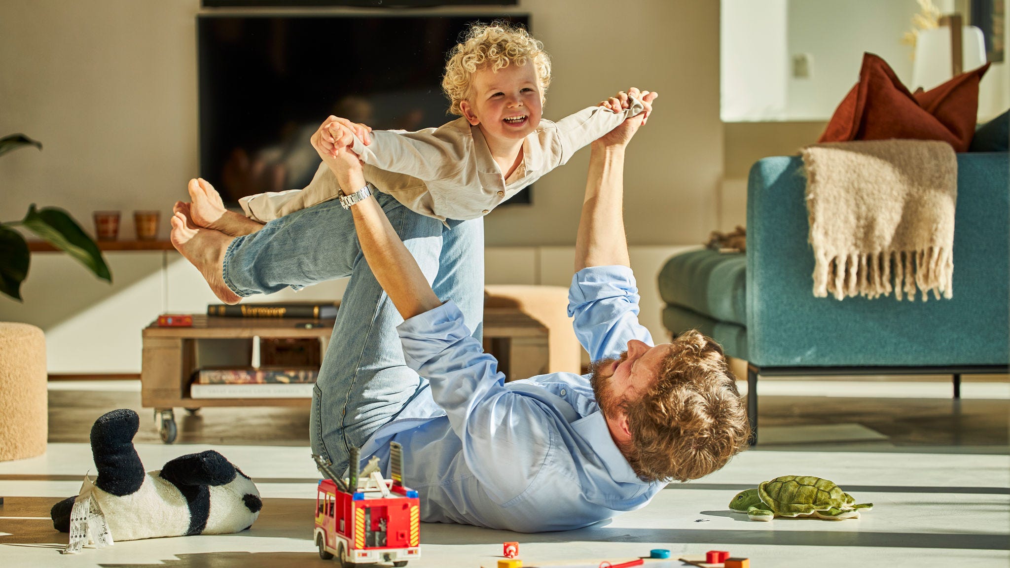 Tata i jego dziecko szczęśliwie bawią się razem i cieszą się ciepłem ogrzewania podłogowego