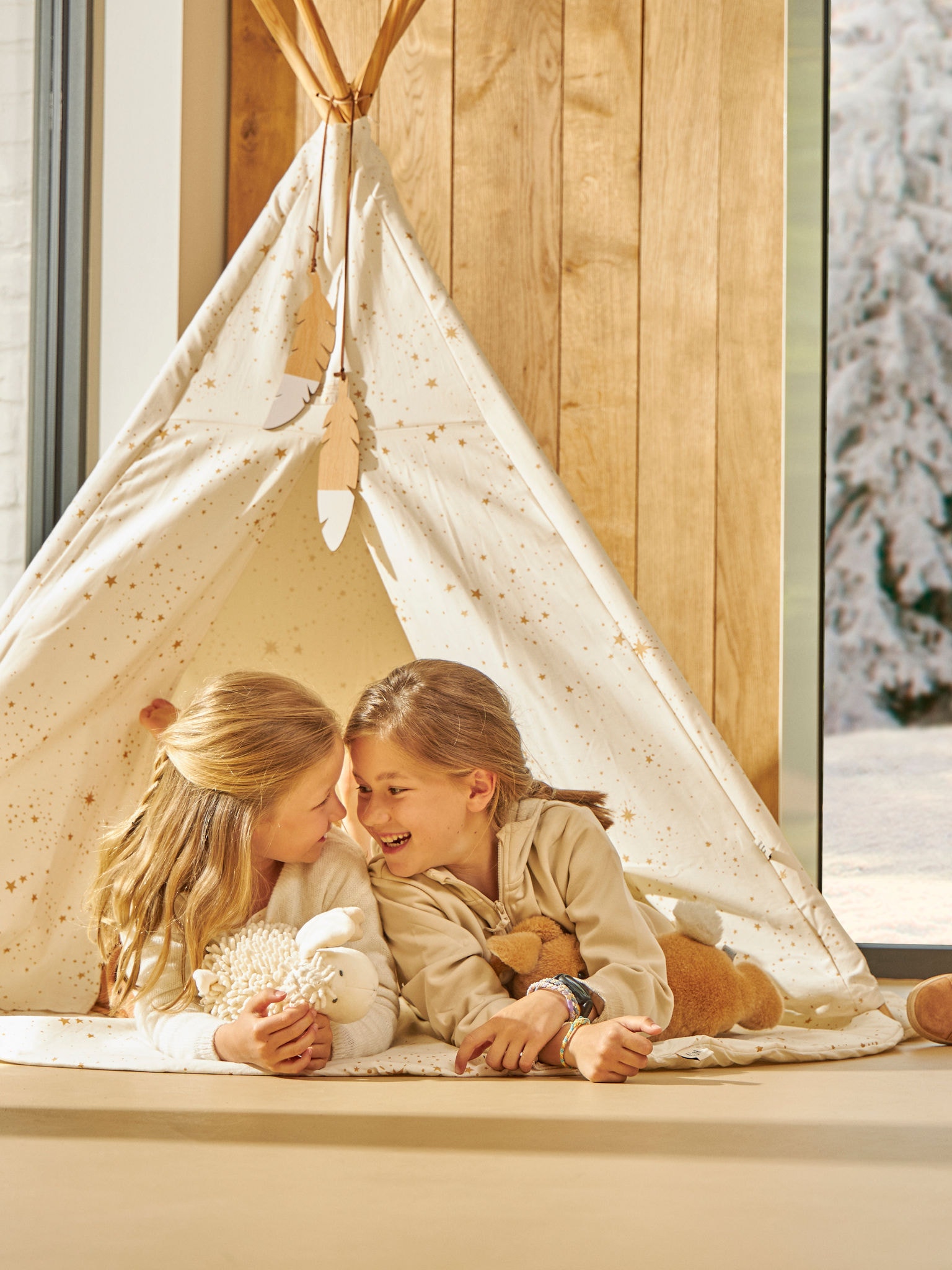 Dwoje małych dzieci radośnie bawi się w swoim namiocie wewnętrznym w idealnej temperaturze.