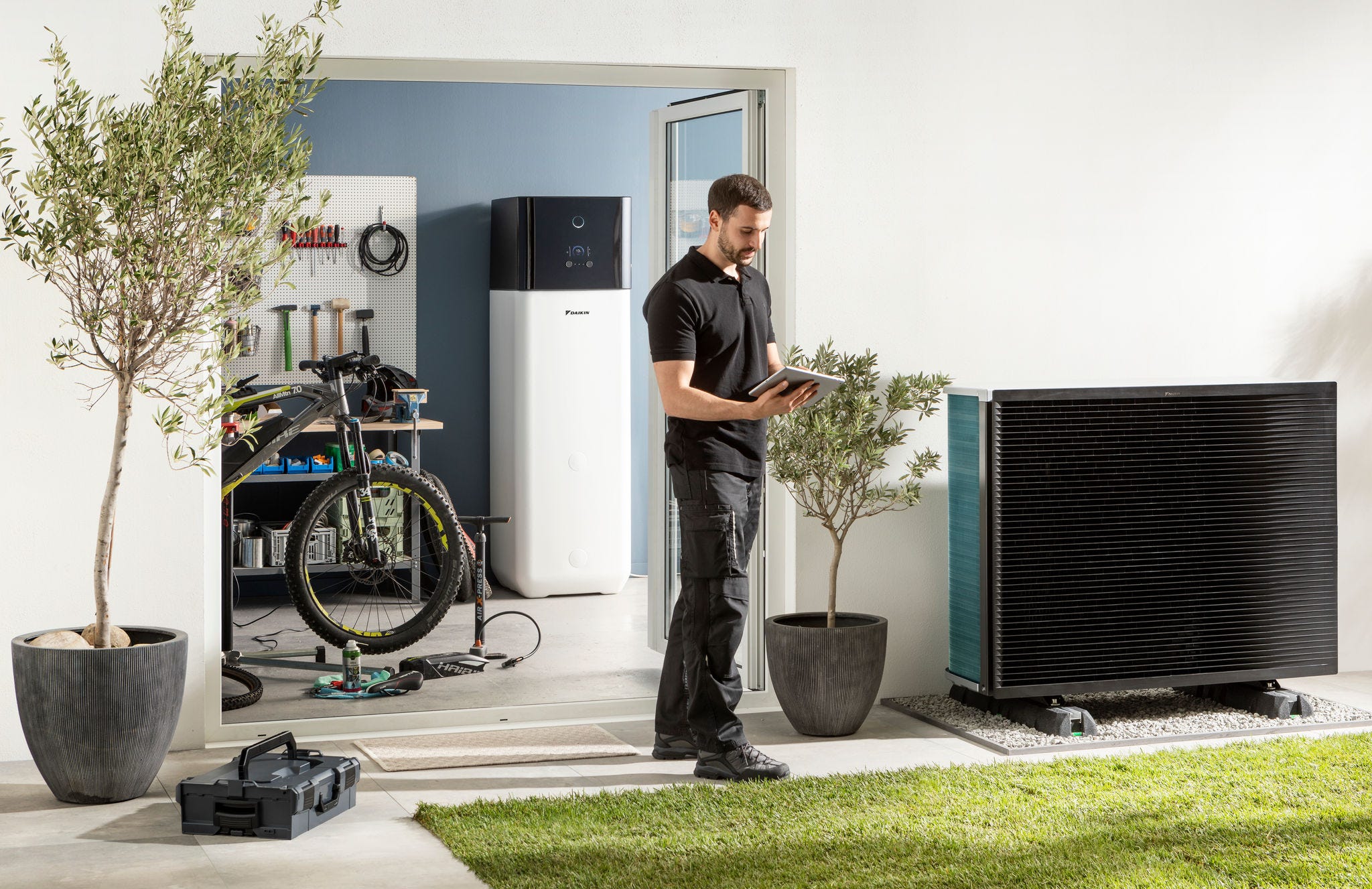Instalator sprawdzający jednostkę zewnętrzną powietrznej pompy ciepła oraz zbiornik ciepłej wody użytkowej