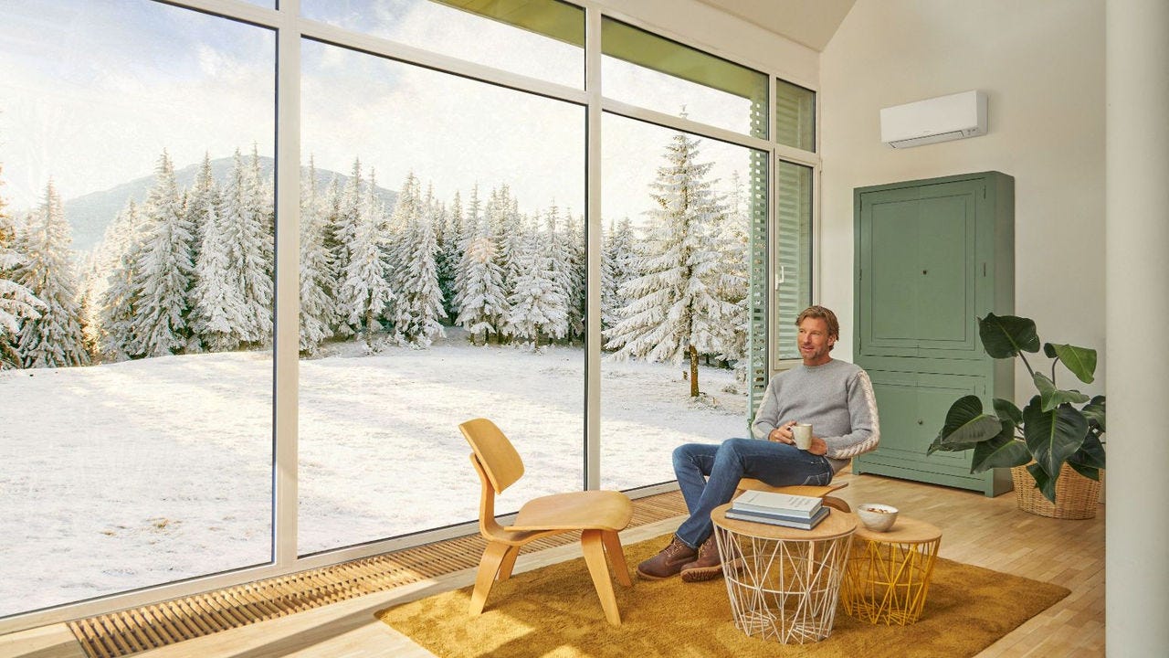 Mężczyzna siedzący na kanapie i korzystający z ogrzewania za pomocą klimatyzatora.