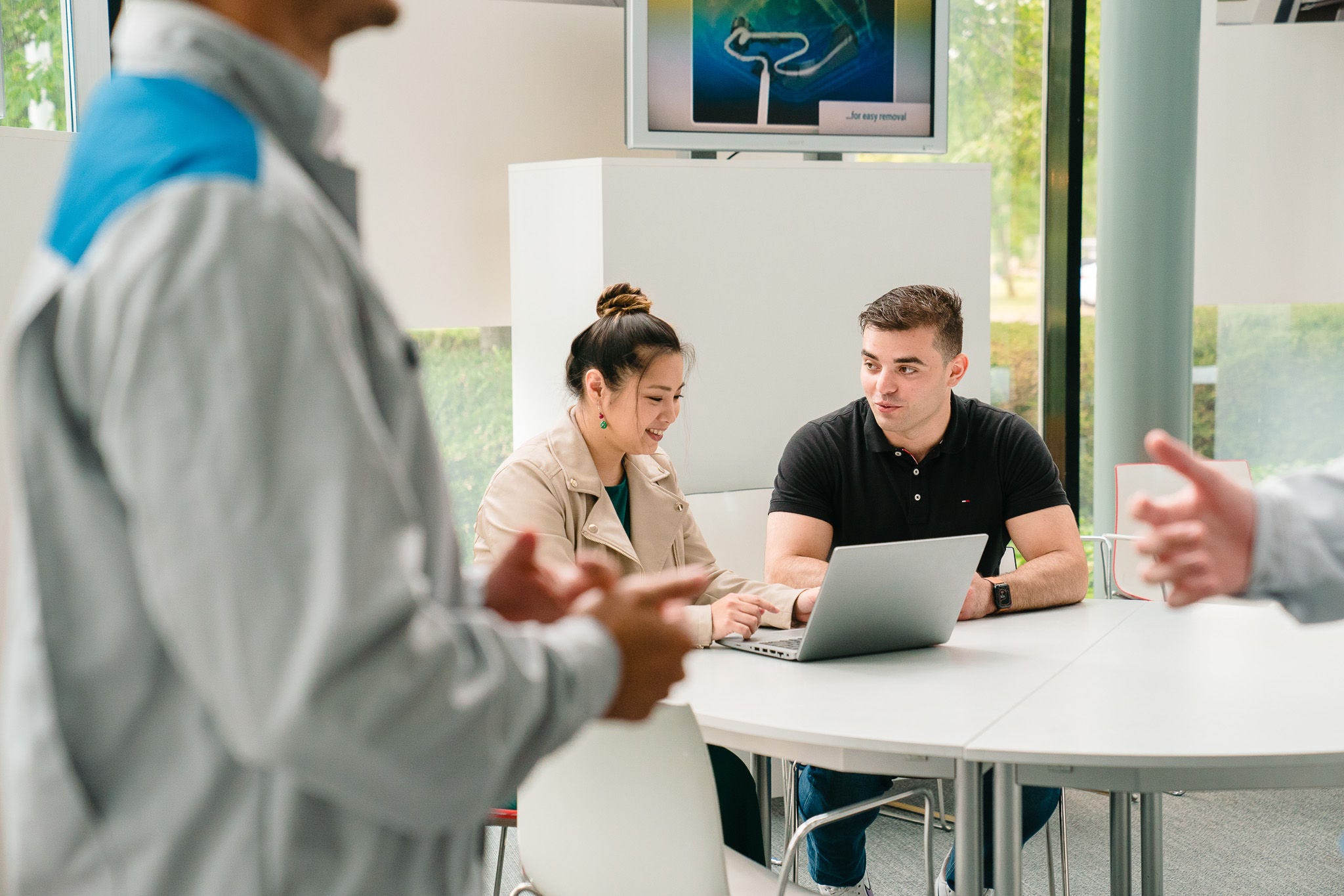 Kobieta tłumacząca mężczyźnie coś na laptopie.
