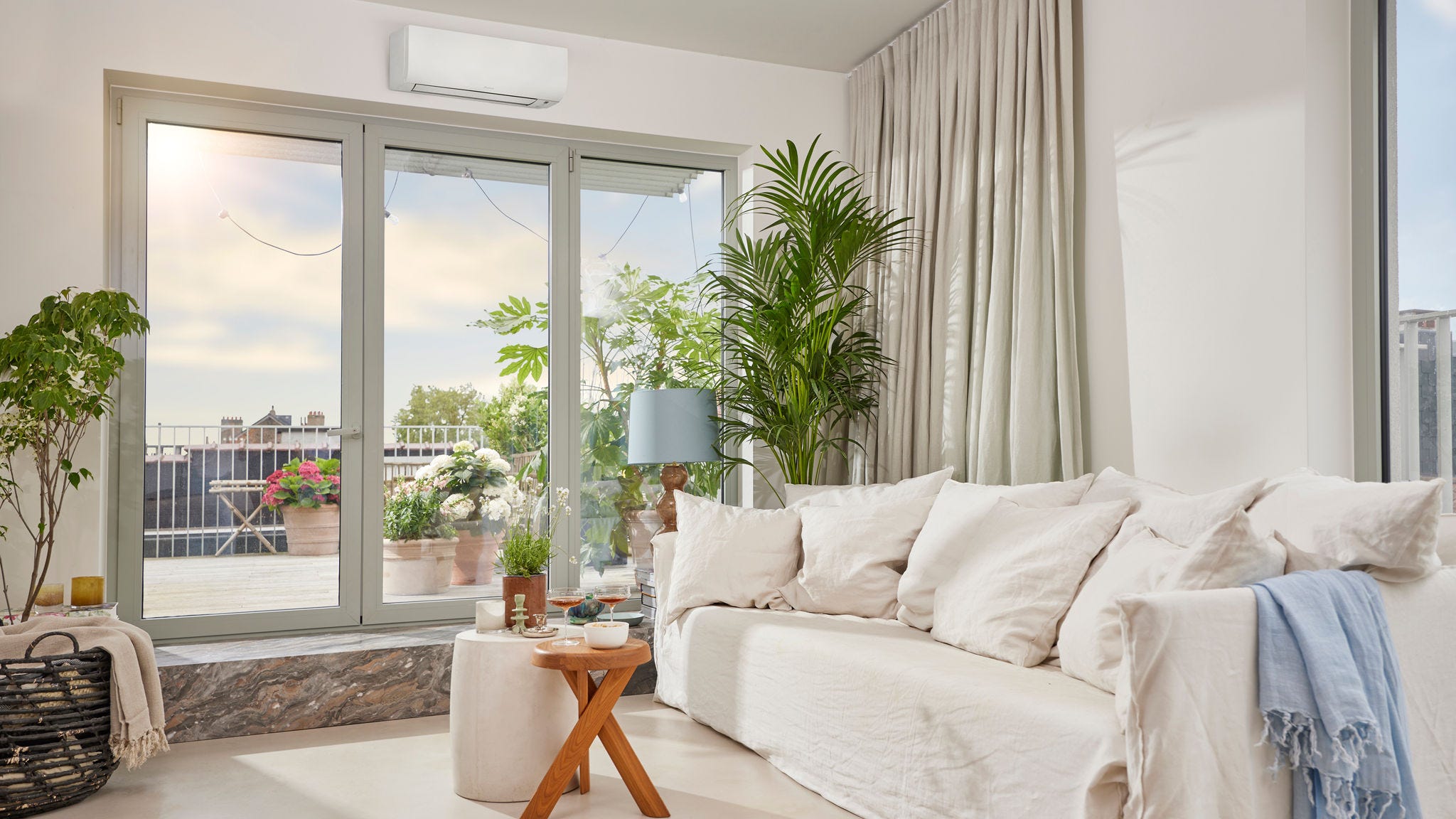Jasny, przestronny pokój z dyskretną białą, naścienną pompą ciepła powietrze-powietrze, zapewniającą zarówno jego ogrzewanie, jak i chłodzenie
