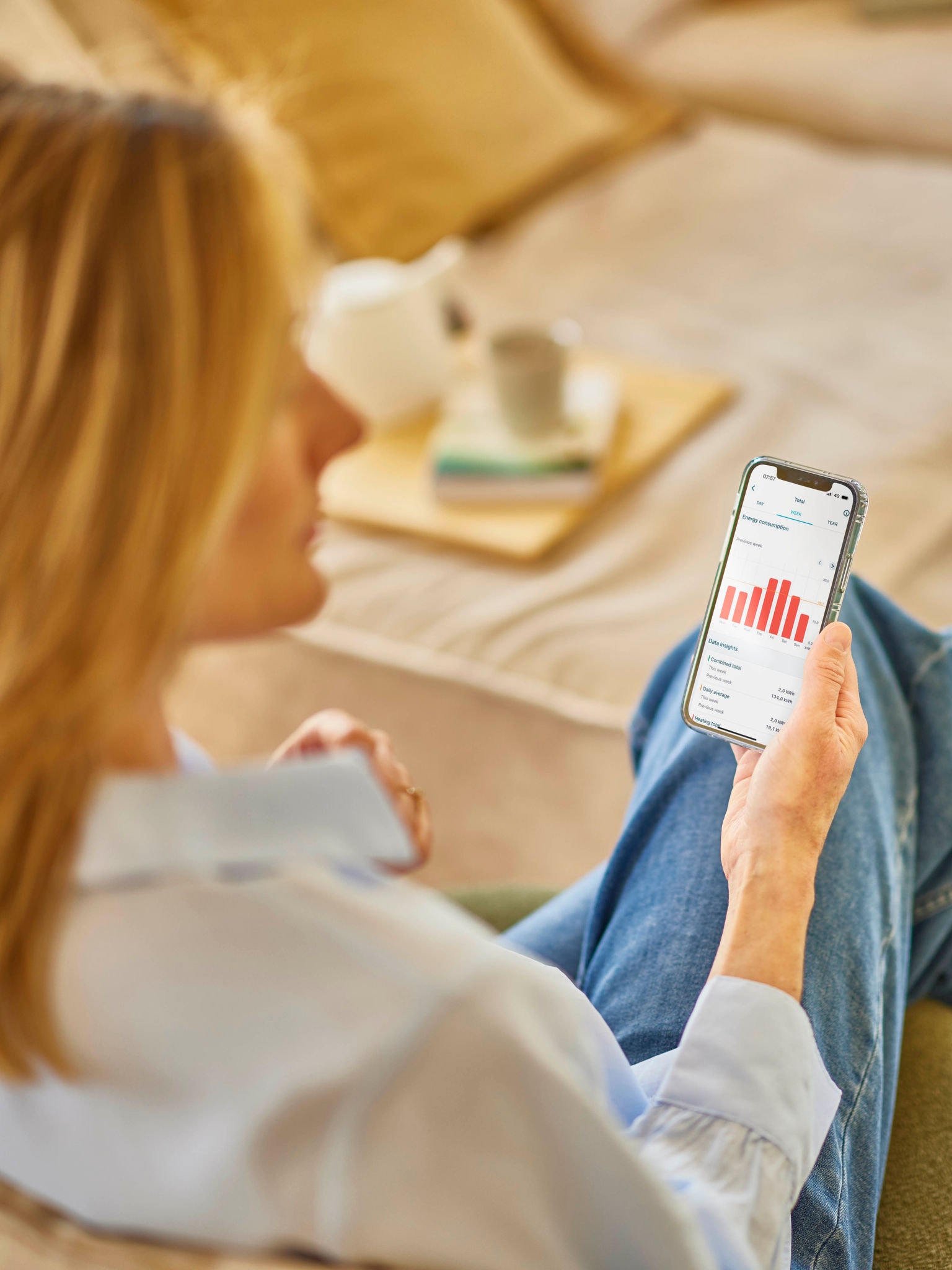 Kobieta o blond włosach sprawdza zużycie energii w aplikacji w swoim telefonie