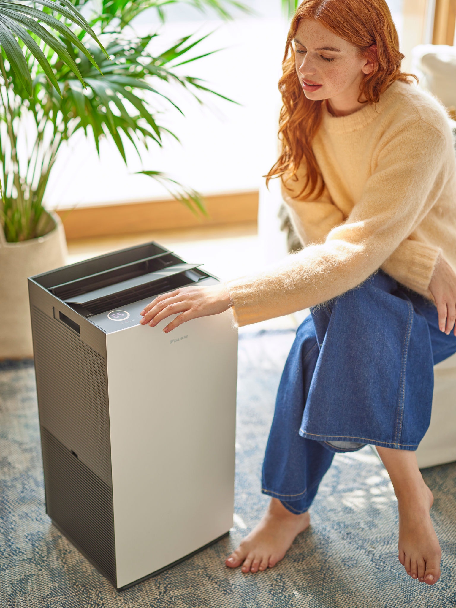Kobieta w salonie reguluje ustawienia oczyszczacza powietrza Daikin