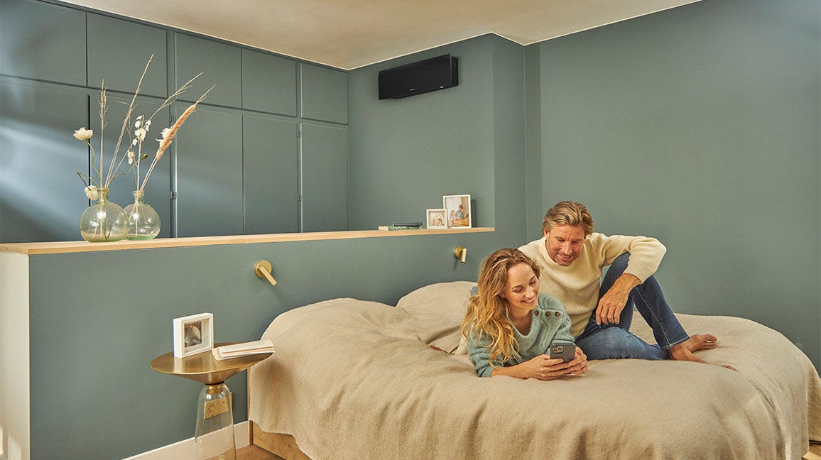 Mężczyzna opierający się o ścianę i patrzący na smartfon.