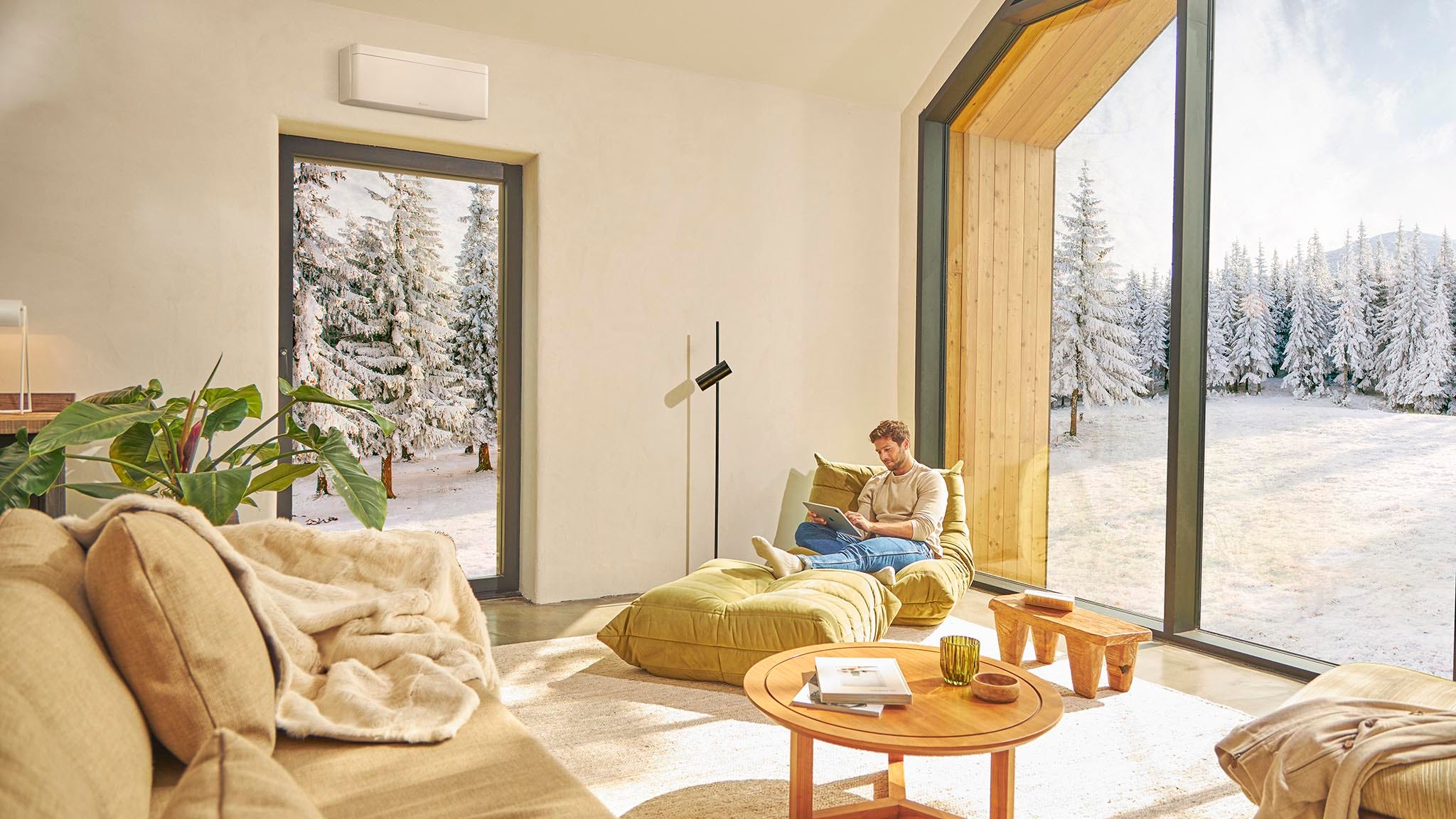 Mężczyzna siedzący na kanapie i korzystający z ogrzewania za pomocą klimatyzatora.