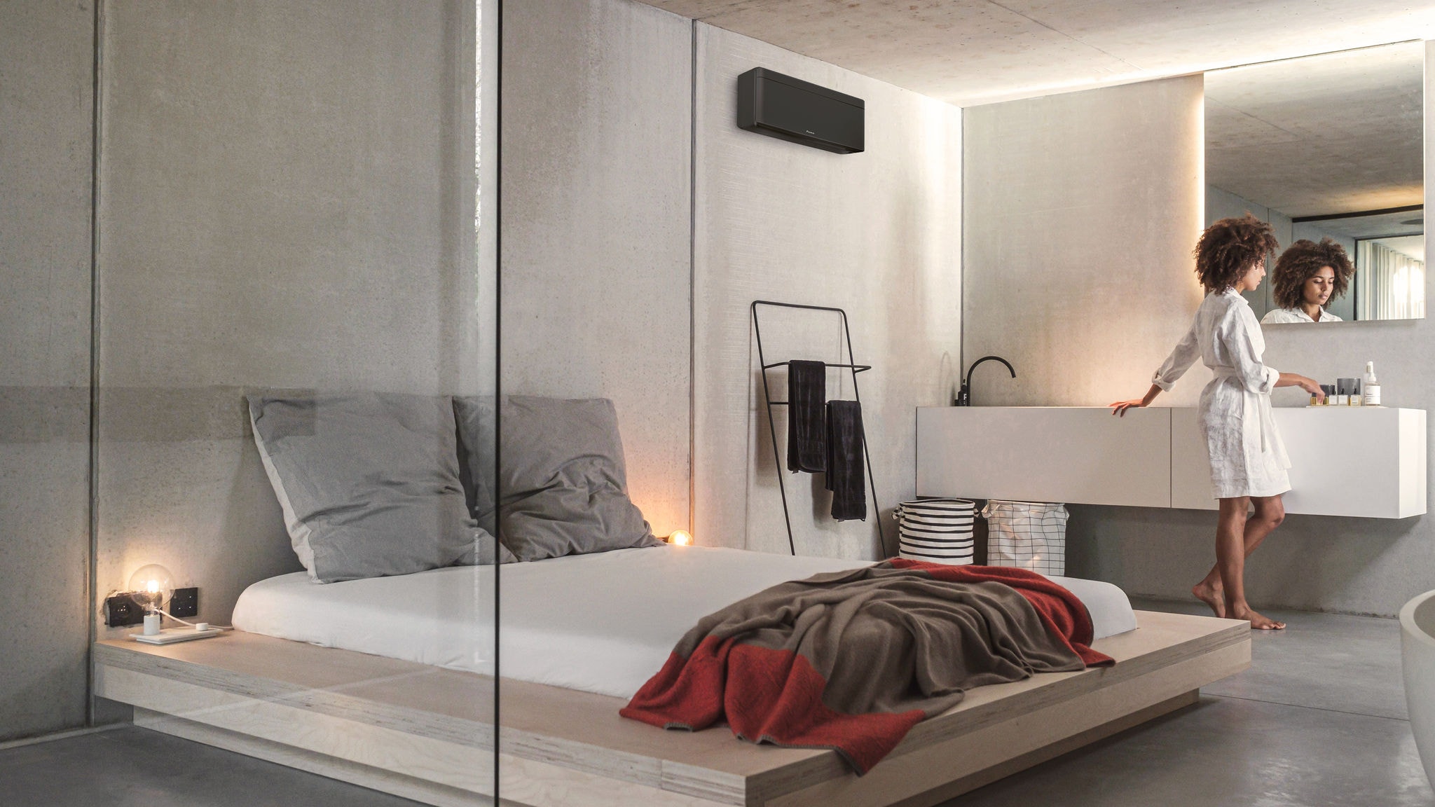 Kobieta przygotowująca się do dnia w swojej sypialni i zintegrowanej łazience klimatyzowanej i ogrzewanej przez jednostkę wewnętrzną Stylish.