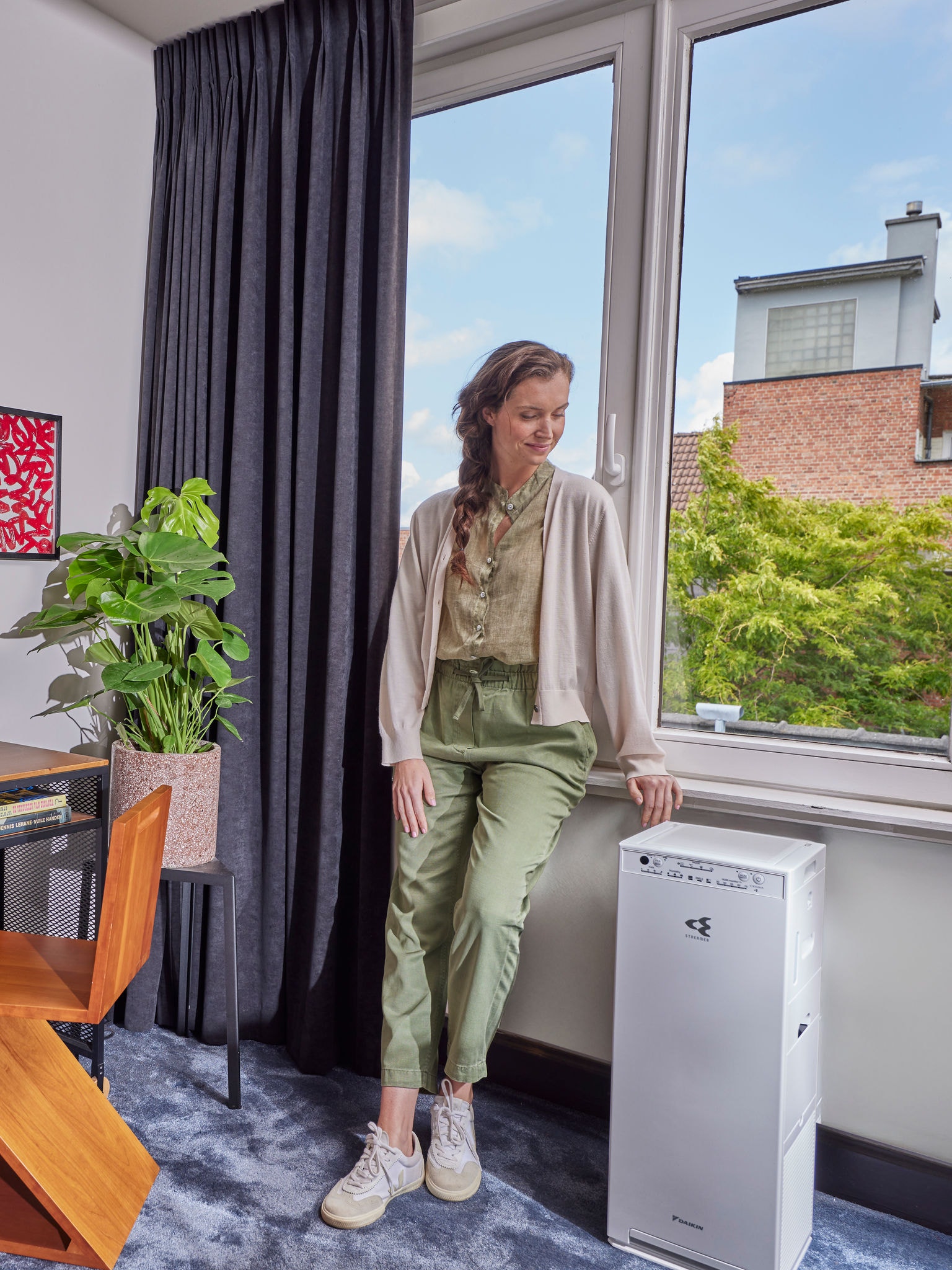 Kobieta stoi obok swojego oczyszczacza powietrza