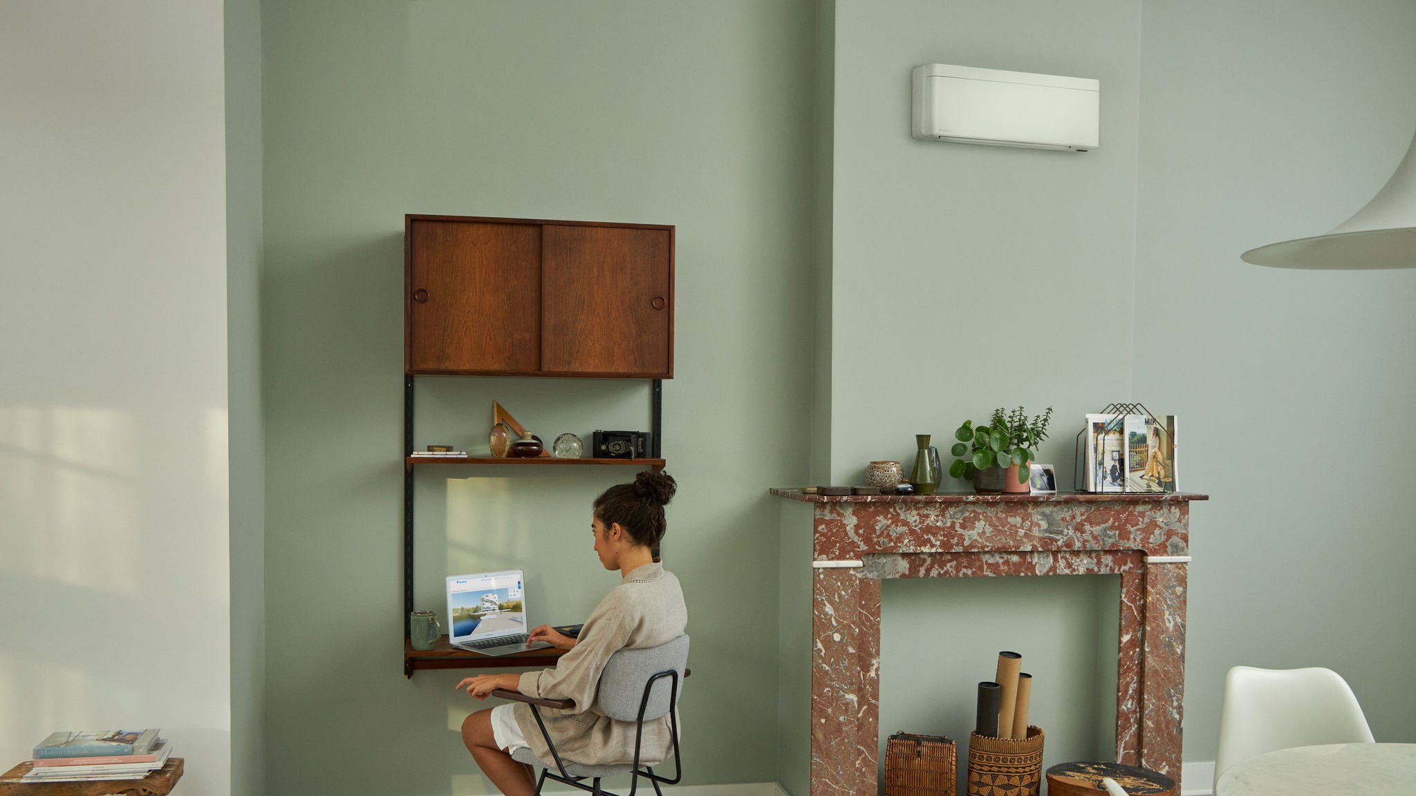 Kobieta odwiedzająca Wirtualne Centrum Doświadczeń Daikin za pośrednictwem laptopa przy małym biurku w pięknie urządzonym salonie.